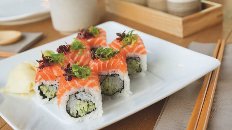 Salmon and cucumber sushi in white plate on wooden table