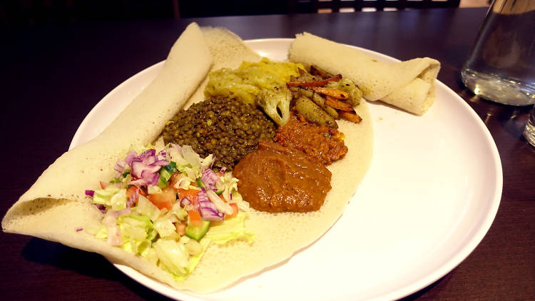 Injera flatbread with five kinds of curried vegetables and salad served on top at Blue Nile African Cuisine and Cafe