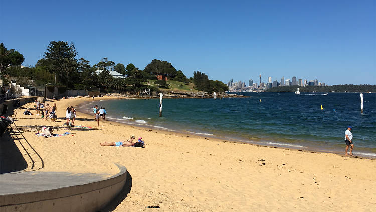 Camp cove beach looking out onto Sydney Harbour with the city skyline in the background