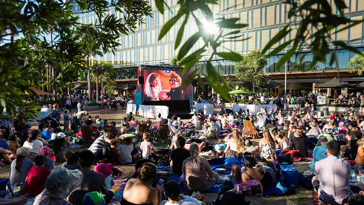 Families enjoy a film outside at the Village Green