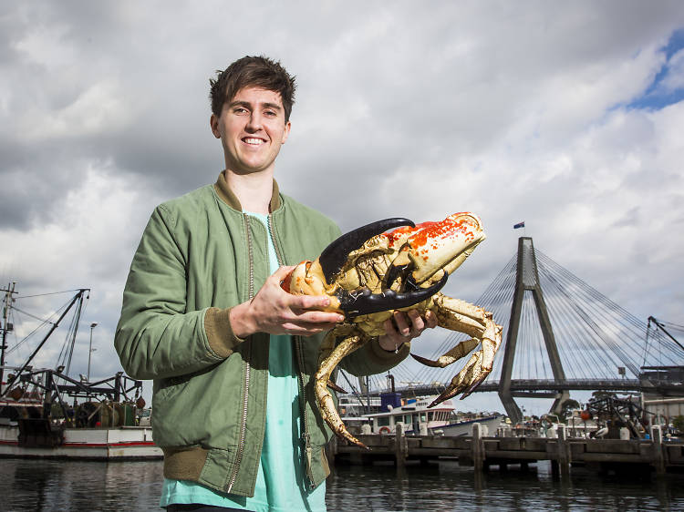 Chef Josh Niland holding a king crab outside the fish markets