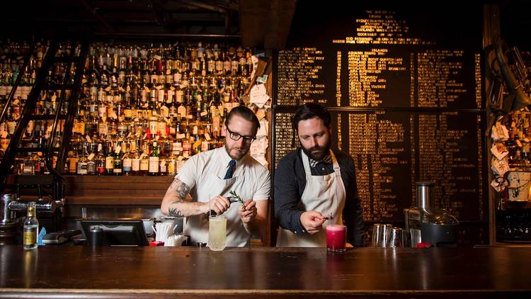 Two bartenders pouring whisky