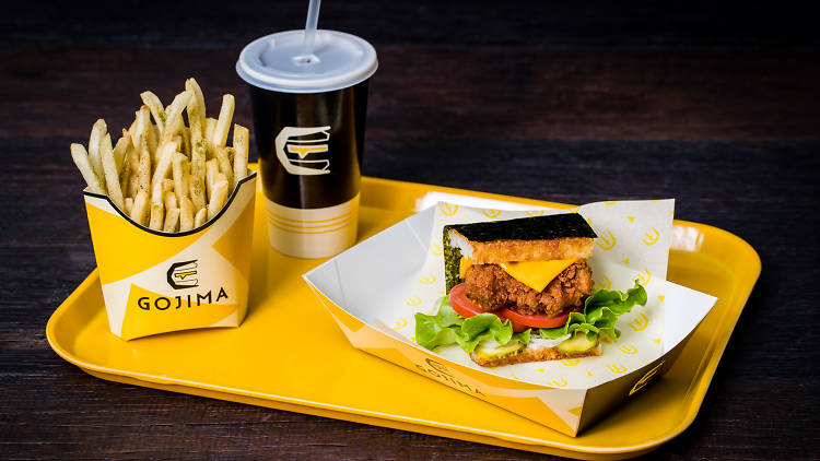 A rice burger, fries and a drink on a plastic tray