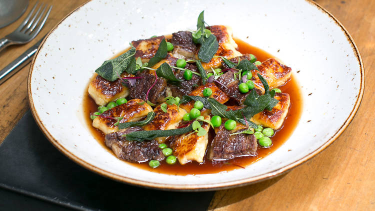 A plate of gnocchi with beef and peas