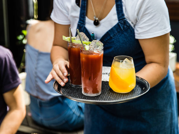 A waiter carries of tray of Bloody Mary and Mimosa cocktails during brunch at Surry Hills bar Dead Ringer