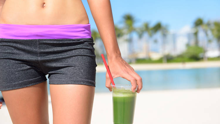 Woman with green juice on the beach