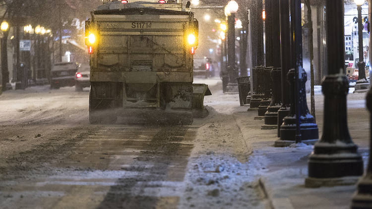 A snow plow truck clears the road and lays down salt during the first major winter storm in Chicago.