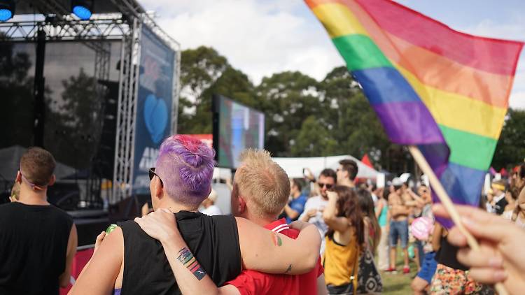 Attendees enjoy an act onstage at Fair Day in front of the Rainbow Flag 