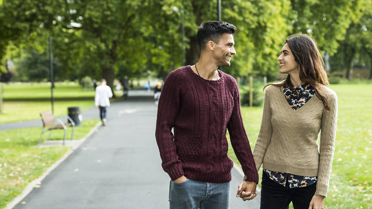 A couple look into each other's eyes while holding hands in the park