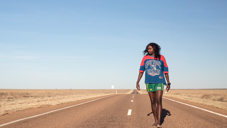 Baker Boy walking on a road in the desert