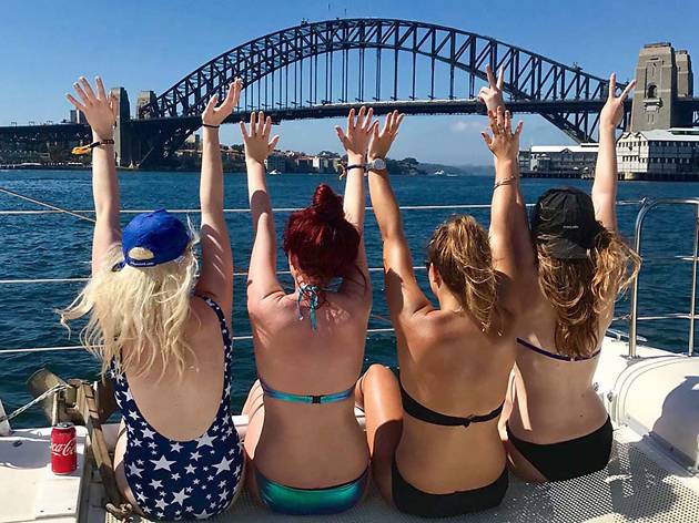 Women with their hands in the air, looking at Sydney Harbour Bridge