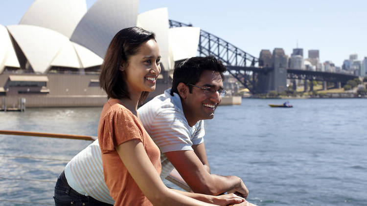 Two people on a boat in front of Sydney Opera House and Bridge