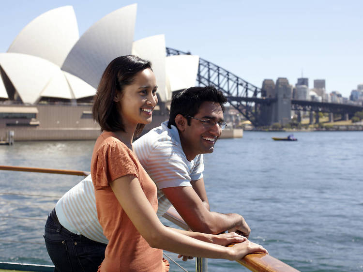 Two people on a boat in front of Sydney Opera House and Bridge