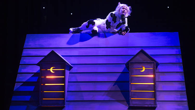 A person in a cat costume sits on a barnyard roof.