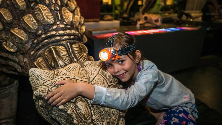 Kid hugs model dinosaur.