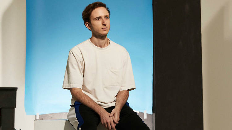 Press release photo of RL Grime sitting on plinth in front of blue background