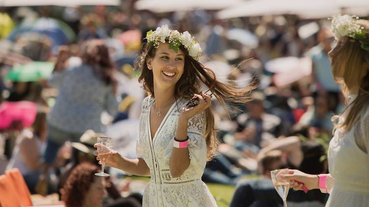 Woman walks through a crowd with a glass of bubbles.