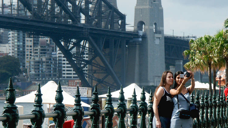 Tourist taking photos in front of the Sydney Harbour Bridge