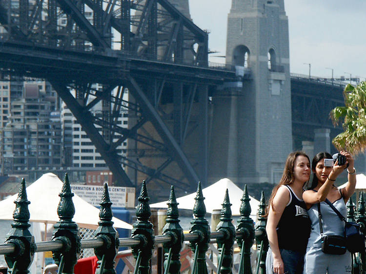 Tourist taking photos in front of the Sydney Harbour Bridge