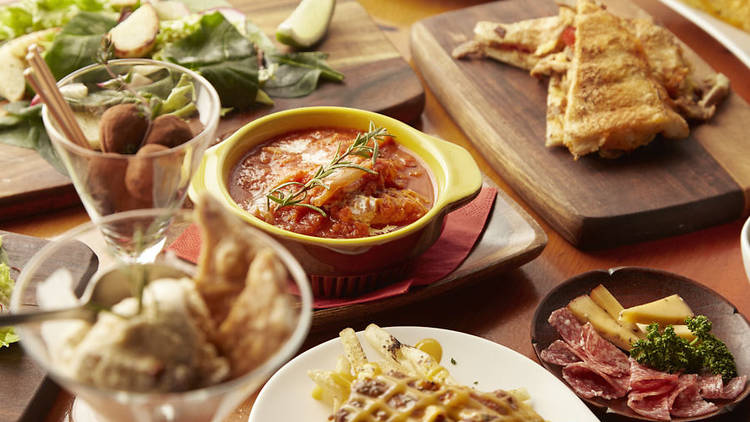 A table covered with food, including toasted sandwiches, salad, ice cream, cured meat and cheese