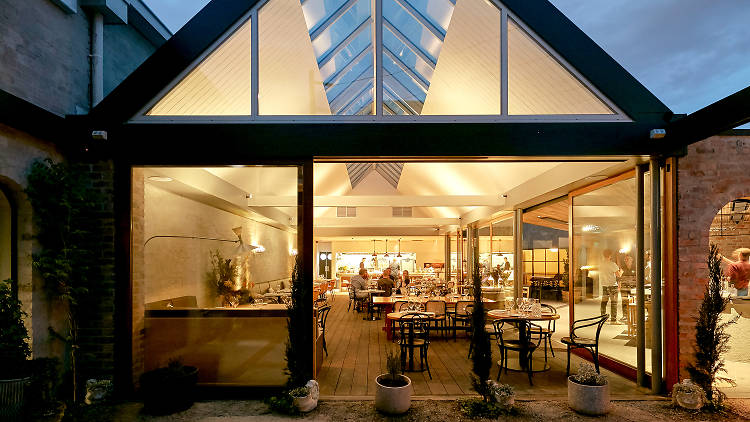 A glasshouse restaurant lit up at night