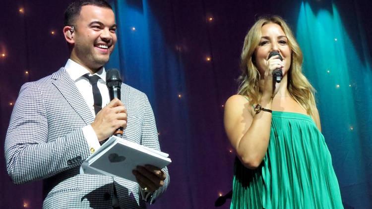 Guy Sebastian and his wife on stage with microphones.