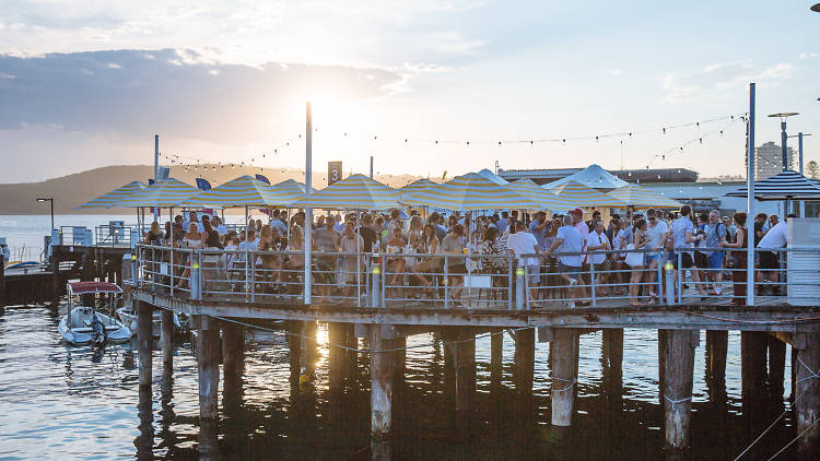 People standing on the wharf over the water at sunset.