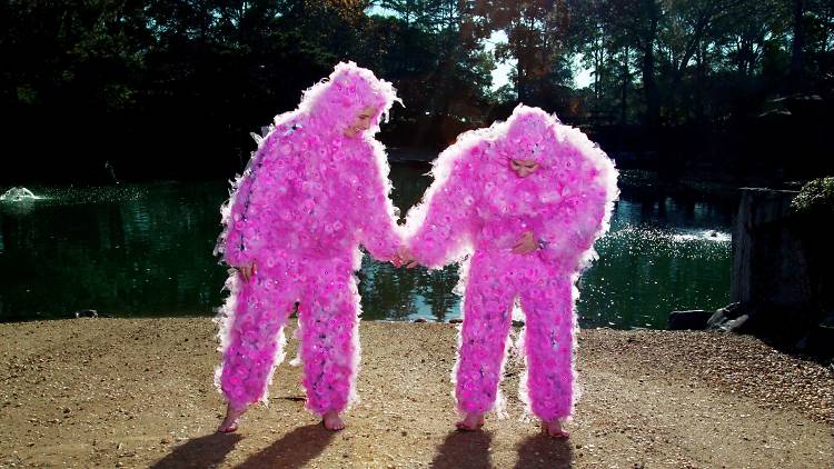 People dressed in pink costumes dance.