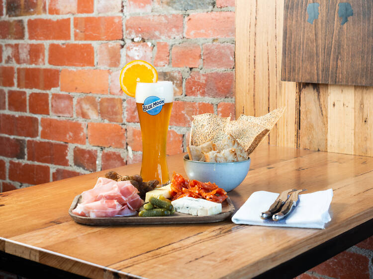 A cheese and cured meats board with a Blue Moon beer