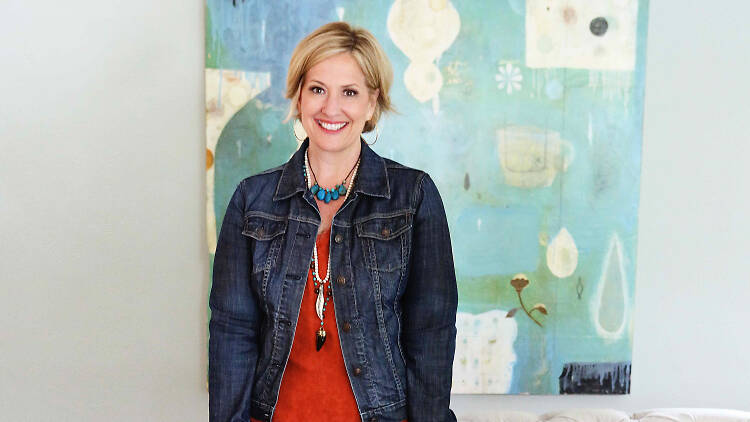 Woman stands in front of a painting.