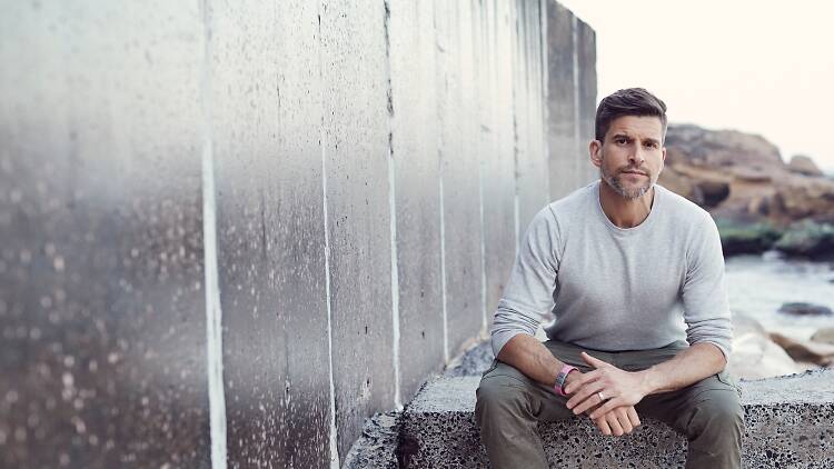 Osher Günsberg sits on a step.