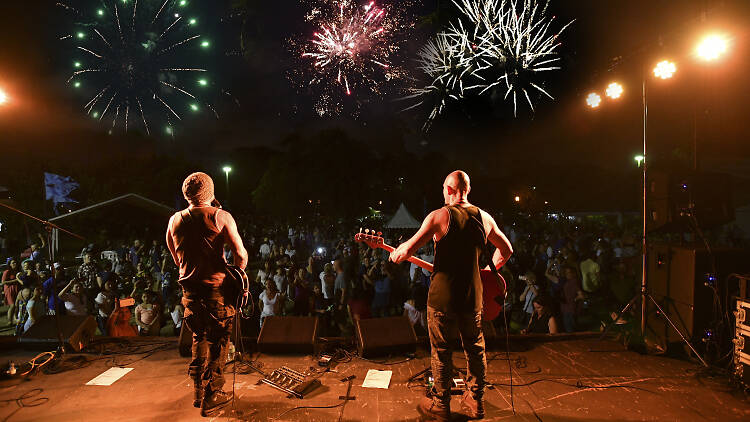 Band plays on stage to crowd and fireworks.