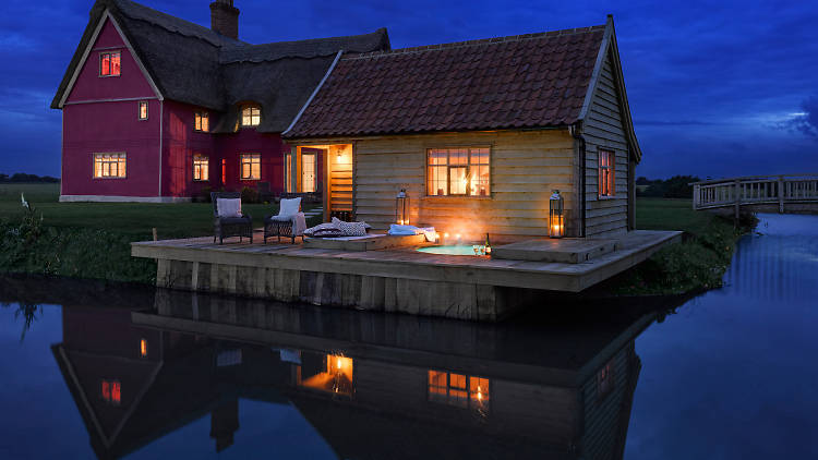 A pink thatched cottage with its own moat