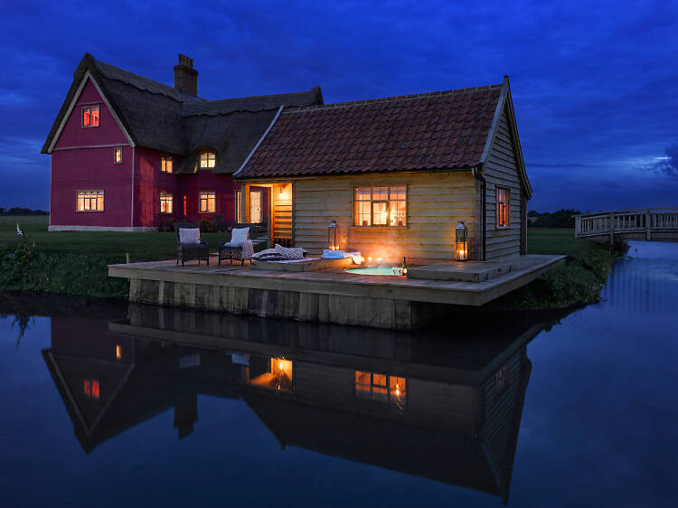 A pink thatched cottage with its own moat