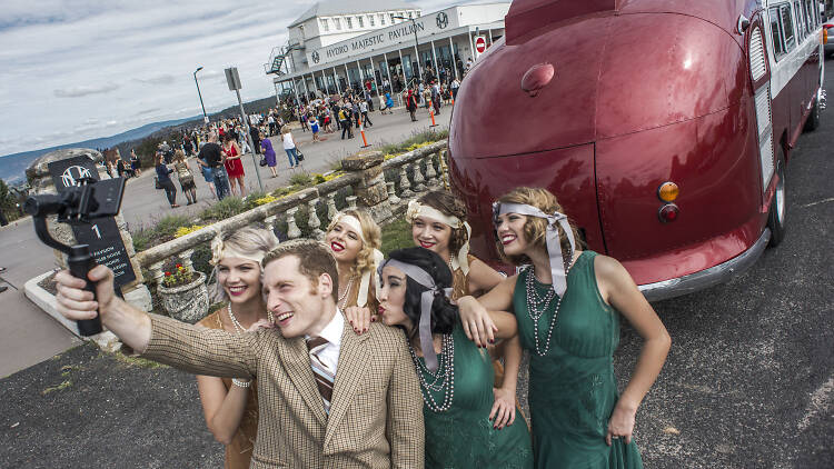 People in 1920s outfits posing for a picture at the Roaring 20s Festival.