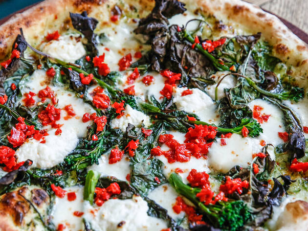 A close up shot of a cheese, capsicum and basil pizza