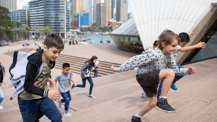 Kids running up the stairs of the Sydney Opera House on the Junior Adventure Tour.