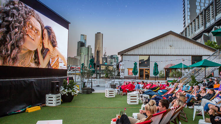 People seated on deckchairs to watch a movie on a big screen