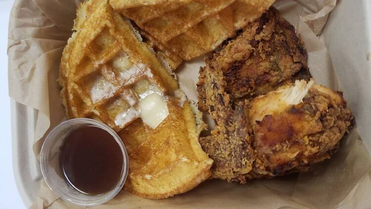 Waffles and fried chicken with a ramekin of syrup