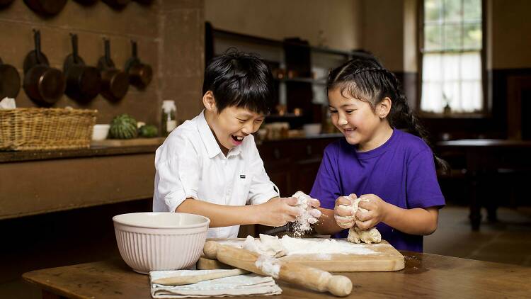 Two children preparing scone dough in the kitchen at Vaucluse House