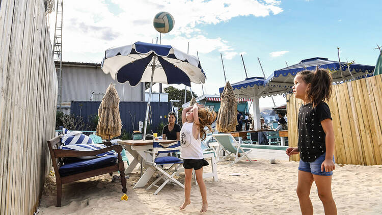 Children in the sand playing with a beach volleyball