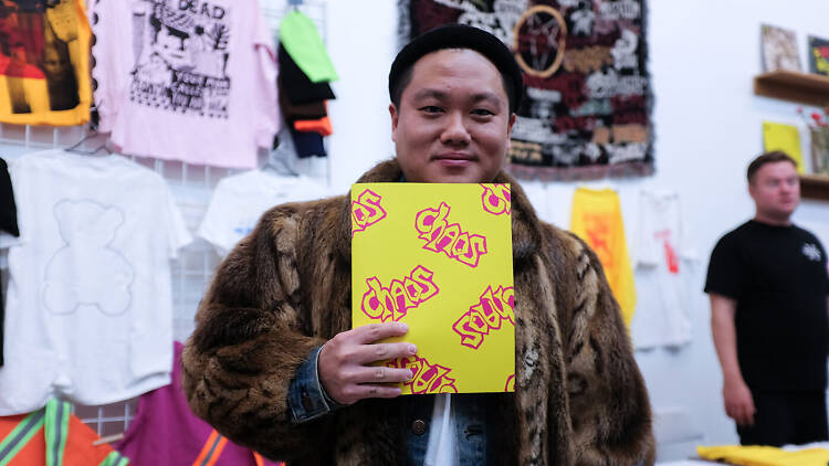Man in fur coast holding up zine