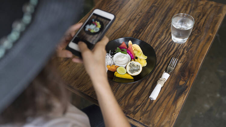 Woman taking a picture of food on a plate with smartphone
