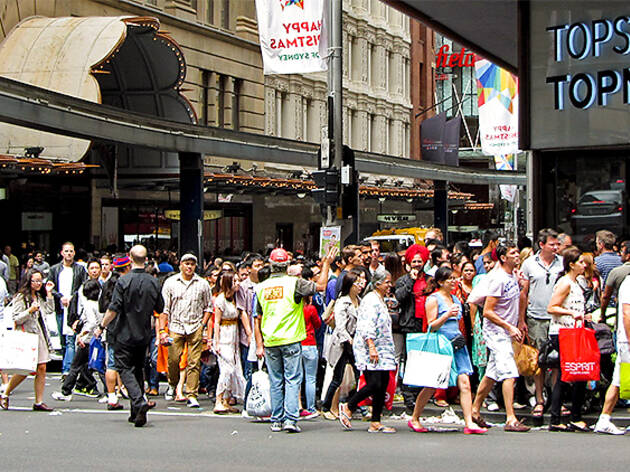 Boxing Day sydney People spilling onto the roads everywhere. There's a man in a yellow vest trying to sell copies of The Big Issue. Nobody is interested.
