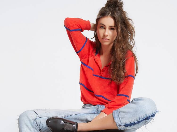 Musician Amy Shark wearing a red top and jeans, sitting