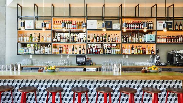 A geometric tiled bar with red stools