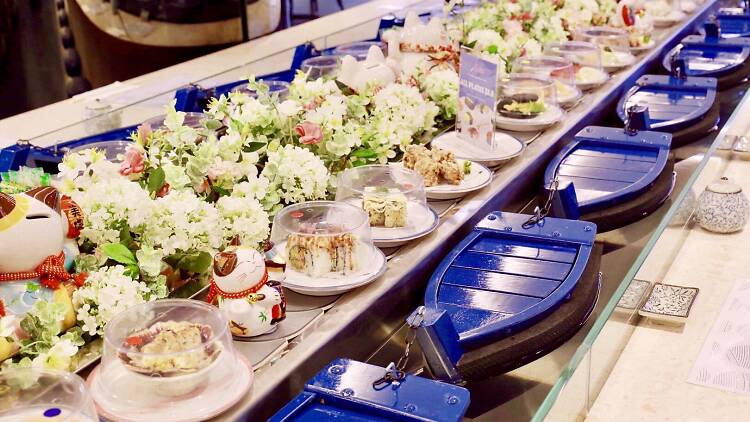 A sushi train that uses tiny boats in a canal instead of rails