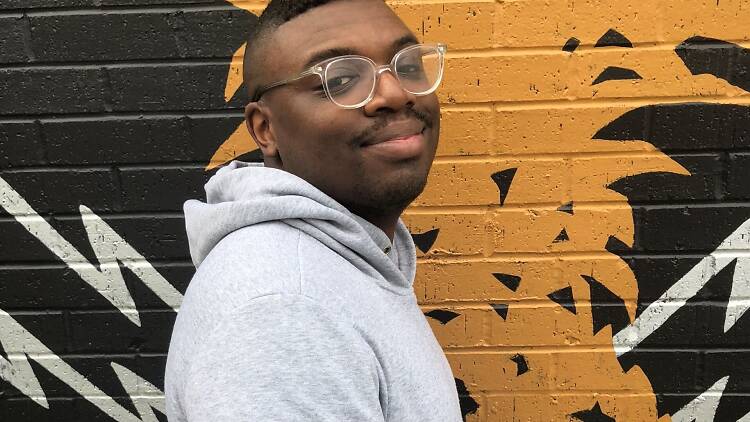 Writer Bryan Washington standing by a wall