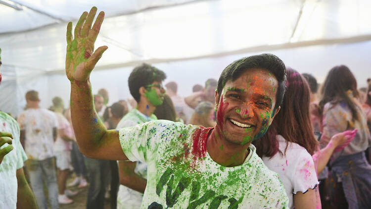 Man smiling while covered in coloured powder