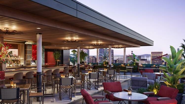 The roofdeck at Everdene with a view of the skyline and red lounge seating
